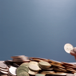 N looking up at a variety of coins, cards, and banknotes spread out on a table against a blue backdrop