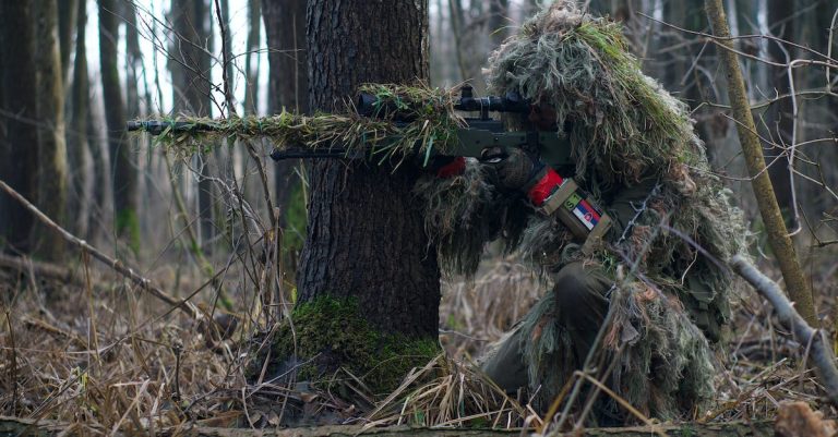 a-soldier-sniper-aiming-though-the-rifle-scope-in-forest