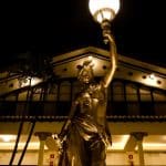 a statue of a woman holding a lamp in front of a building