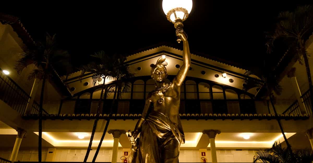 a-statue-of-a-woman-holding-a-lamp-in-front-of-a-building