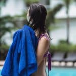 alluring young woman wiping wet hair with towel on poolside