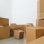 stack of carton boxes of various shapes and sizes scattered in floor near white walls during relocat