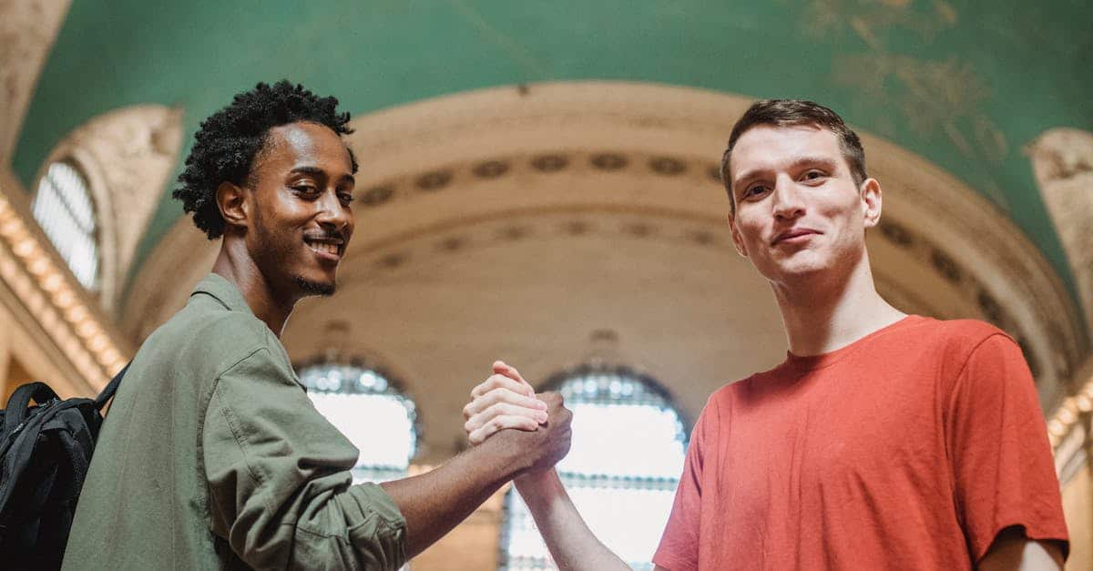 from-below-of-positive-young-multiethnic-male-friends-in-casual-clothes-smiling-and-looking-at-camer